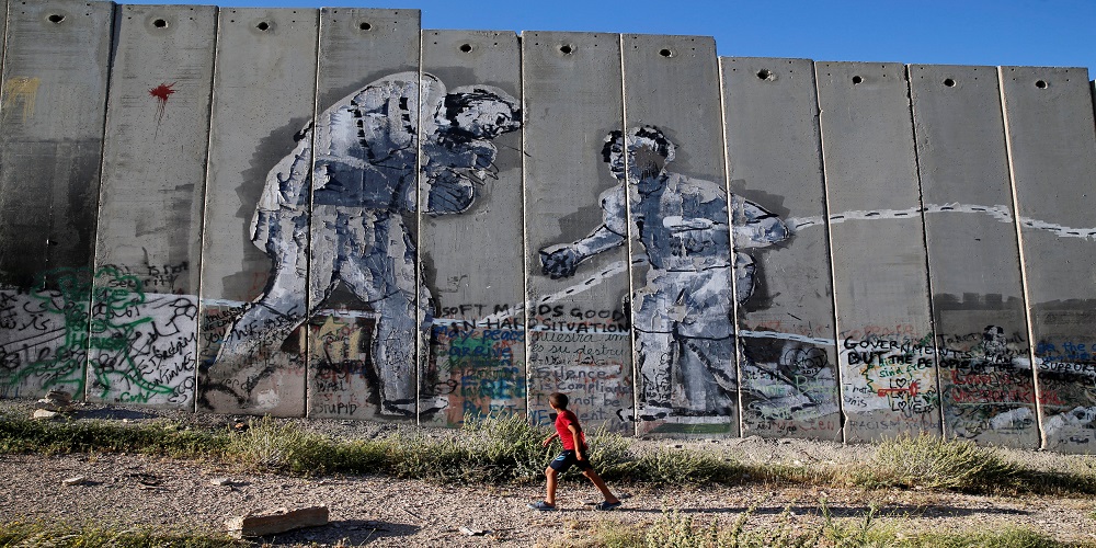 طفل فلسطيني يسير بجانب جدار الفصل العنصري